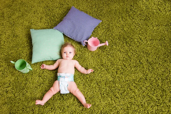 Küçük bebek yeşil halı üzerinde yer alır. — Stok fotoğraf