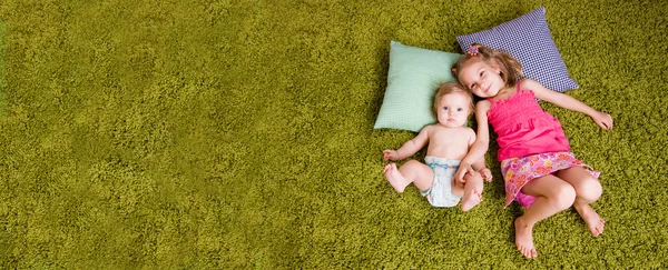 Two happy sisters lie on carpet — Stock Photo, Image