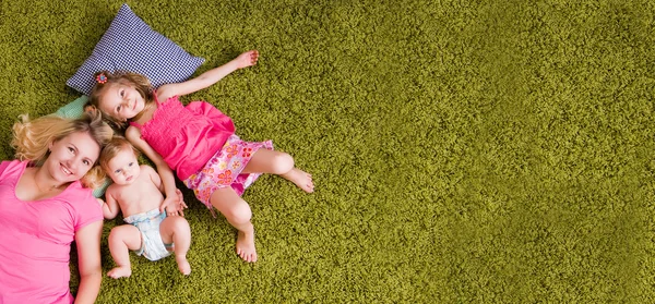 Мать и двое детей лежат на ковре — стоковое фото