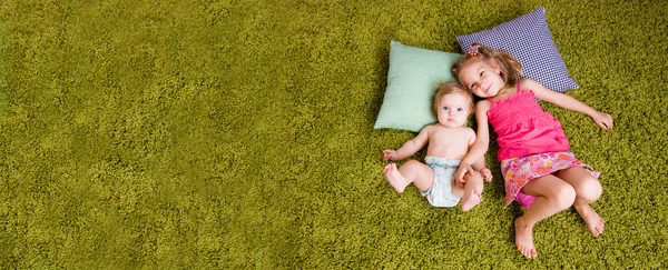 Two happy sisters lie on carpet Royalty Free Stock Images