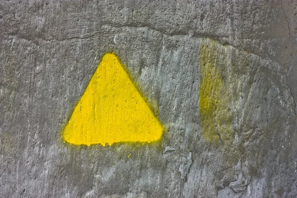 Серая бетонная стена с желтым треугольником — стоковое фото