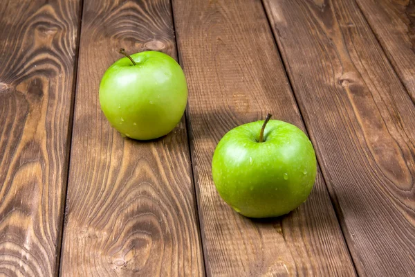 Duas maçãs verdes em um fundo de madeira — Fotografia de Stock