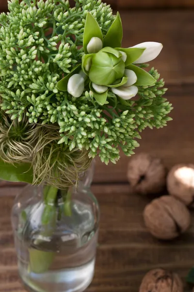 Still life with green flowers and lily on a wooden background — Stock Photo, Image