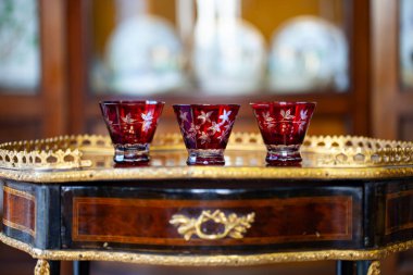 Rönesans tarzı bir iç mekanda antika kırmızı şarap kadehleri. Çiçek desenli antika şarap bardakları