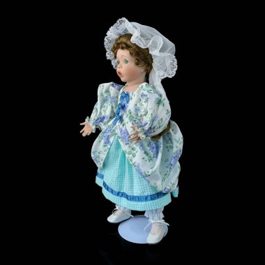 Siyah arka planda izole edilmiş porselen bebek. mavi elbiseli seramik eski bir bebek.