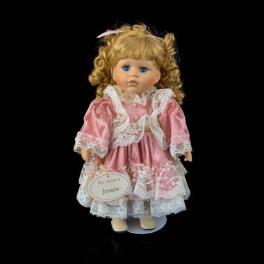 Siyah arka planda izole edilmiş porselen bebek. Seramik, eski pembe elbiseli yaşlı bir bebek.