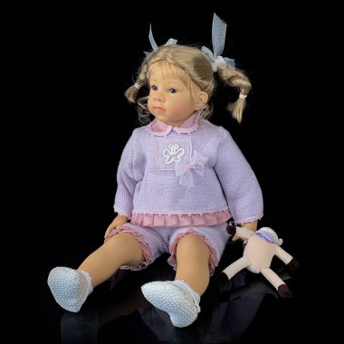 Siyah arka planda izole edilmiş porselen bebek. Pembe takım elbiseli seramik yaşlı bir bebek.