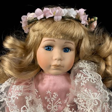 Siyah arka planda izole edilmiş porselen bebek. Eski moda pembe elbiseli seramik yaşlı bebek. Yakın plan.