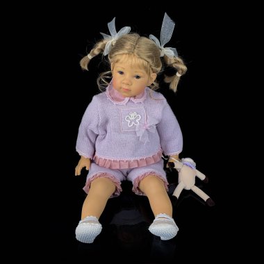 Siyah arka planda izole edilmiş porselen bebek. Pembe takım elbiseli seramik yaşlı bir bebek.