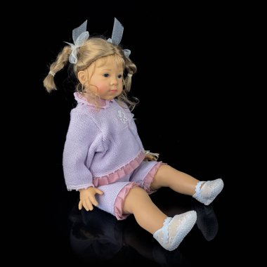 Siyah arka planda izole edilmiş porselen bebek. Pembe takım elbiseli seramik yaşlı bir bebek.
