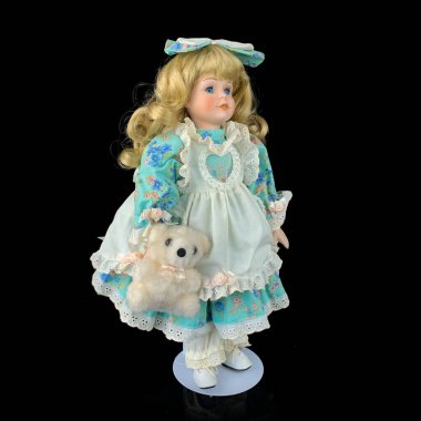 Siyah arka planda izole edilmiş porselen bebek. mavi elbiseli seramik eski bir bebek.