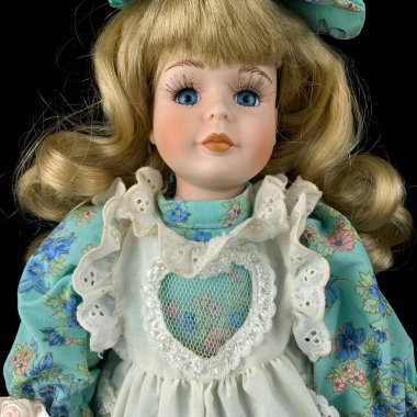 Siyah arka planda izole edilmiş porselen bebek. antika mavi elbiseli seramik eski bir bebek. Yakın plan.