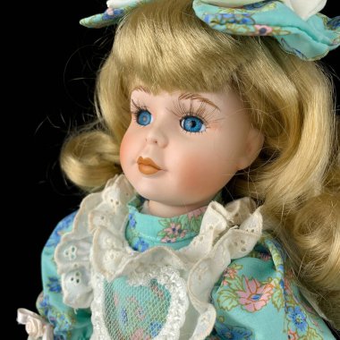 Siyah arka planda izole edilmiş porselen bebek. antika mavi elbiseli seramik eski bir bebek. Yakın plan.