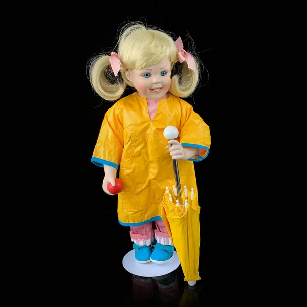 黒の背景に孤立した磁器人形 黄色のレインコートを着たセラミック製の古い人形 — ストック写真