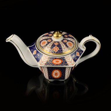 Elle boyanmış antika bir çaydanlık. Siyah izole arkaplanda geometrik desenli retro çay seti