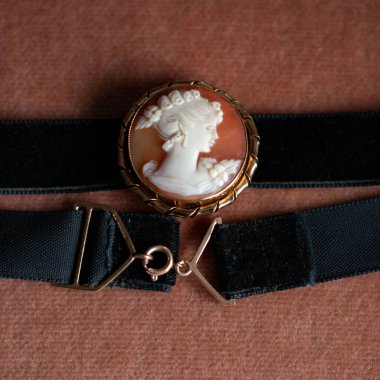 Altın çerçeveli antika bir kolye. Kadın profili olan antika bir broş. Siyah izole arkaplanda klasik boğucu