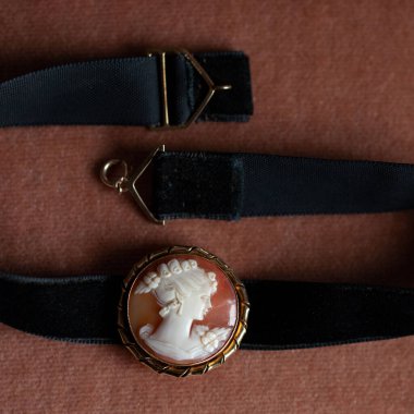 Altın çerçeveli antika bir kolye. Kadın profili olan antika bir broş. Siyah izole arkaplanda klasik boğucu