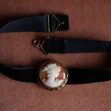 Altın çerçeveli antika bir kolye. Kadın profili olan antika bir broş. Siyah izole arkaplanda klasik boğucu