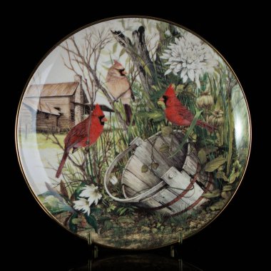 Sonbaharın parlak arka planı, kuş kırmızısı kardinal bir ağaç dalında oturuyor, sarı, turuncu yapraklar dökülüyor. Yuvarlak şekilli. El boyalı antika bir tabak. dekupaj için kuşların görüntüsü ile resim.