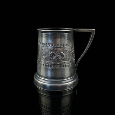 İşlenmiş antik gümüş kupa. Siyah izole arka planda çiçek desenli klasik metal bardak.