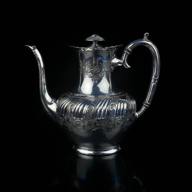 antique metal teapot. silver tea service. metal jug with engraving on a black isolated background. coffee pot