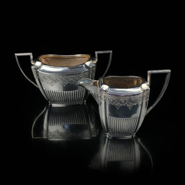 silver antique service with engraving on a black isolated background. vintage tea service.
