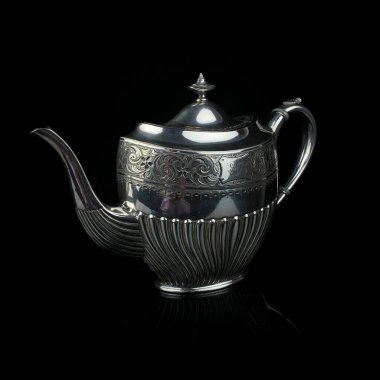 antique metal teapot. silver tea service. metal jug with engraving on a black isolated background