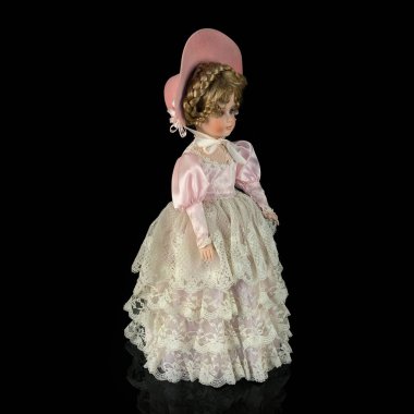 Siyah arka planda izole edilmiş porselen bebek. Seramik, eski pembe elbiseli yaşlı bir bebek.