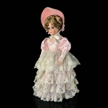 Siyah arka planda izole edilmiş porselen bebek. Seramik, eski pembe elbiseli yaşlı bir bebek.