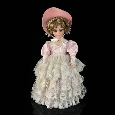 Siyah arka planda izole edilmiş porselen bebek. Seramik, eski pembe elbiseli yaşlı bir bebek.
