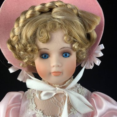 Siyah arka planda izole edilmiş porselen bebek. Seramik, eski pembe elbiseli yaşlı bir bebek.