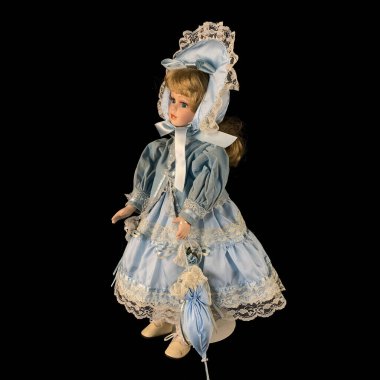 Siyah arka planda izole edilmiş porselen bebek. antika mavi elbiseli seramik eski bir bebek. Yakın plan.