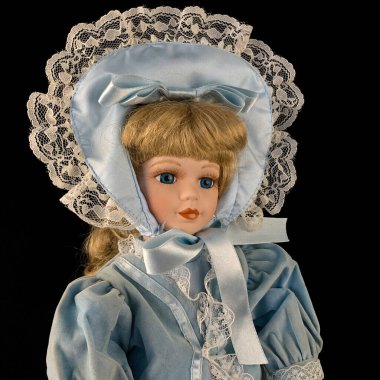 Siyah arka planda izole edilmiş porselen bebek. antika mavi elbiseli seramik eski bir bebek. Yakın plan.