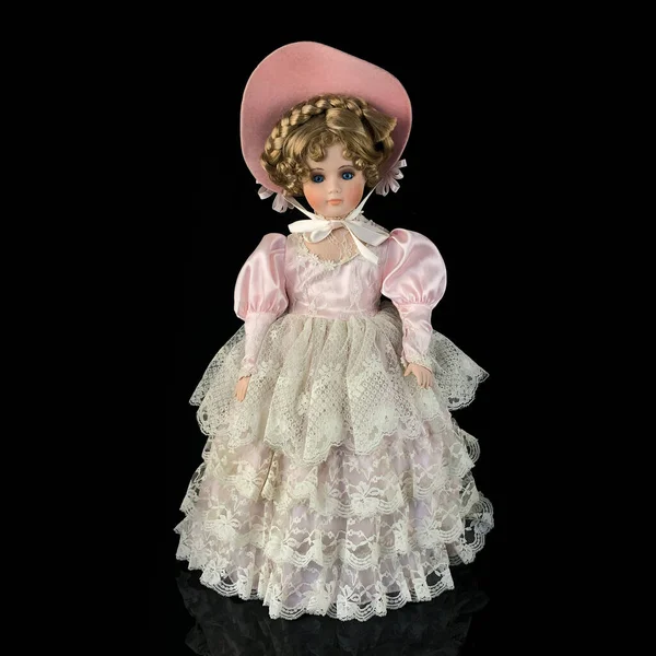 Siyah arka planda izole edilmiş porselen bebek. Seramik, eski pembe elbiseli yaşlı bir bebek.