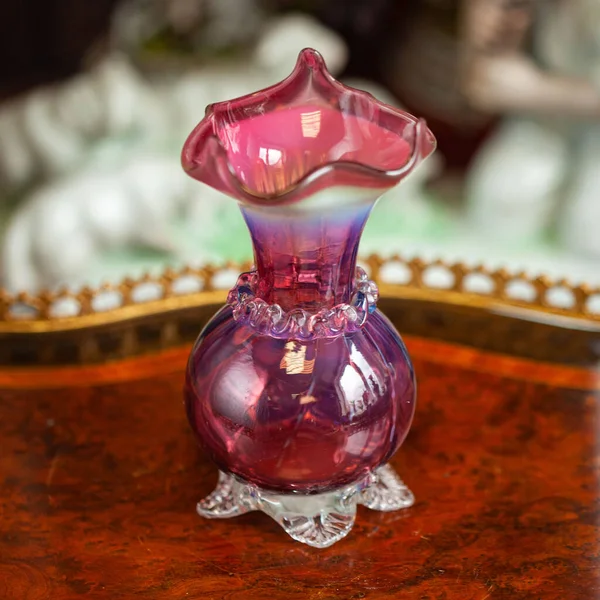 antique pink glass flower vase in the interior. figured pink vase for flowers in a luxury interior. unusual glass vase