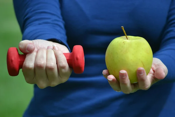 Kvinna med vikter och grönt äpple — Stockfoto