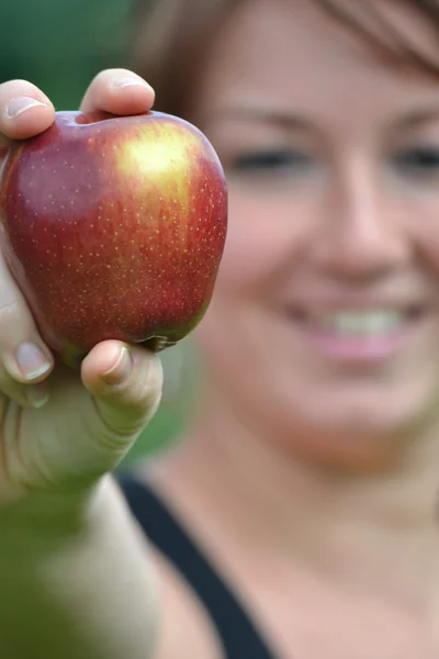 Ung kvinna visar ett äpple — Stockfoto