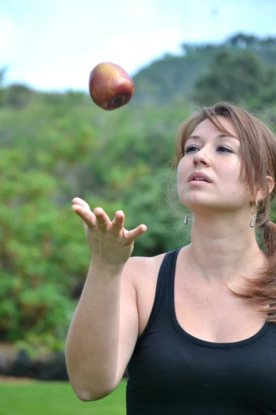 Jeune femme lançant une pomme — Photo