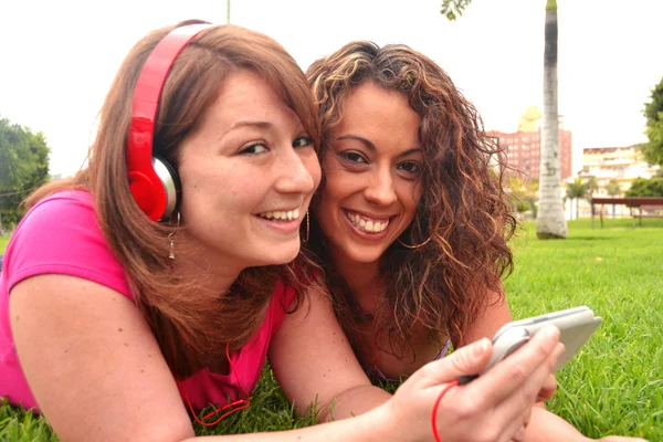 Vrienden luisteren muziek in park — Stockfoto