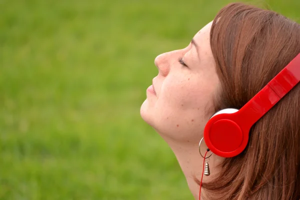 Donna che ascolta musica con auricolare nel parco — Foto Stock