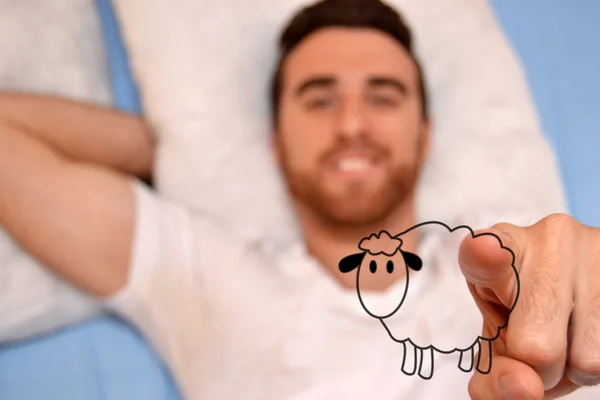 Man lying in bed drawing sheep — Stock Photo, Image