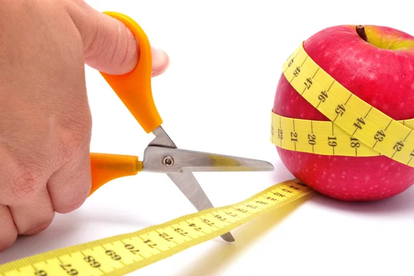 Scissors cutting this tape around an apple — Stock Photo, Image