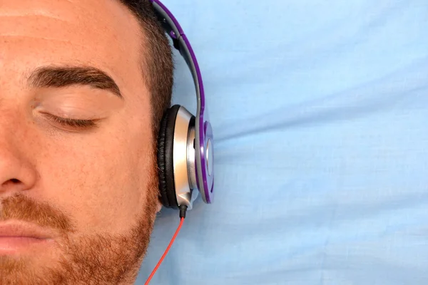 Hombre con auriculares en la cama —  Fotos de Stock