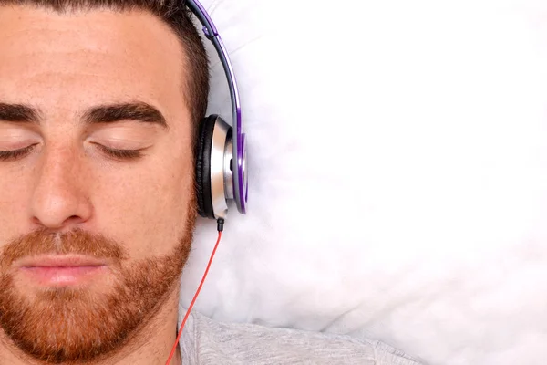 戴着耳机在床上的男人 — 图库照片