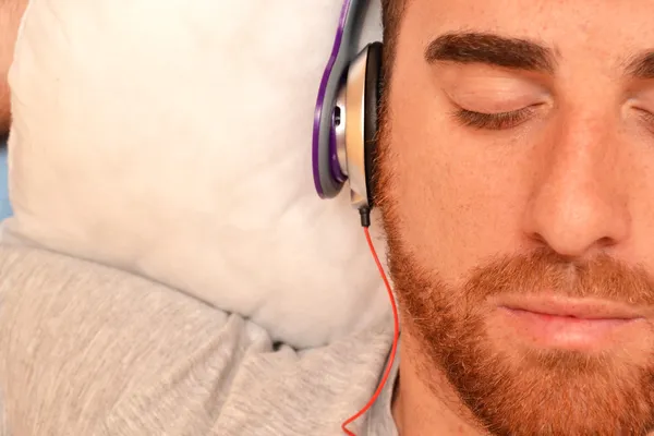 Man met hoofdtelefoon in bed — Stockfoto