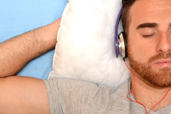 Homem com fones de ouvido na cama — Fotografia de Stock