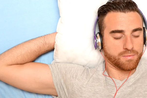 Hombre con auriculares en la cama —  Fotos de Stock