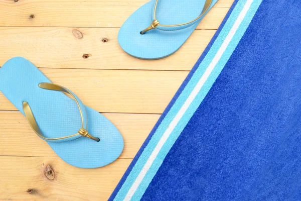 Towel and beach slippers on wood — Stock Photo, Image