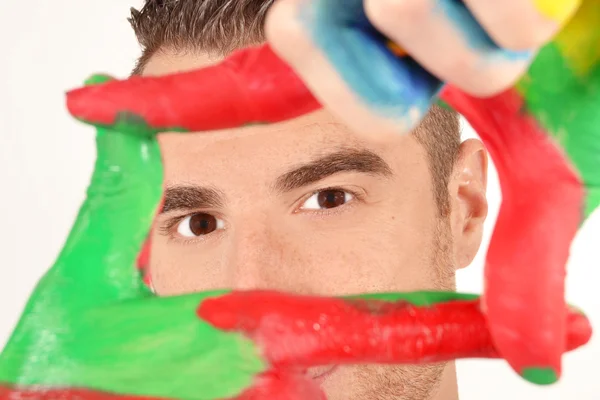 Man looking into the camera with painted hands — Stock Photo, Image