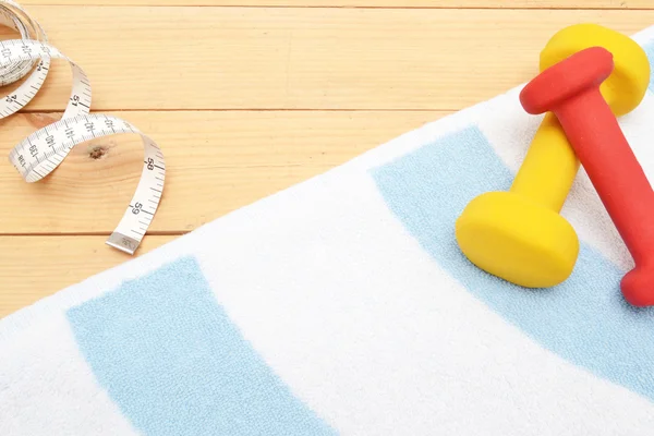 Мера ленты, гантели и пляжное полотенце — стоковое фото